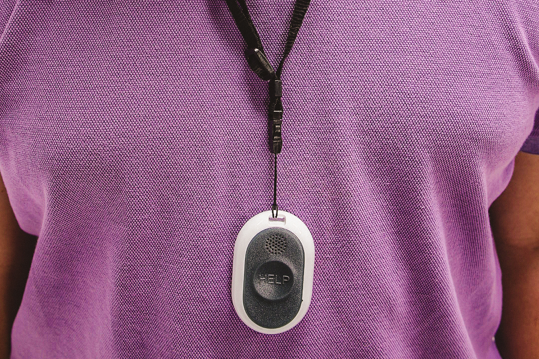 Man shown from chest to hips wearing a fall detection device on lanyard