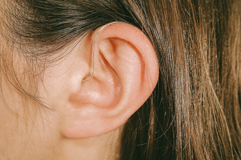 A white woman with brown hair wears a Jabra Enhance hearing aid
