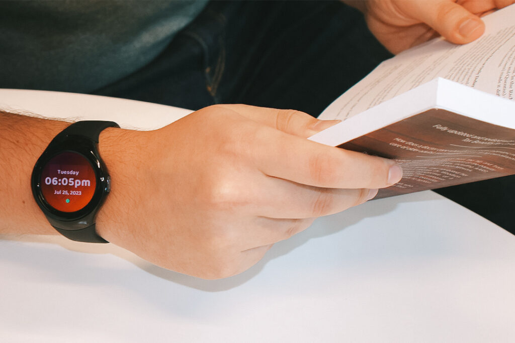 Person reading a book with the MGMove on their wrist