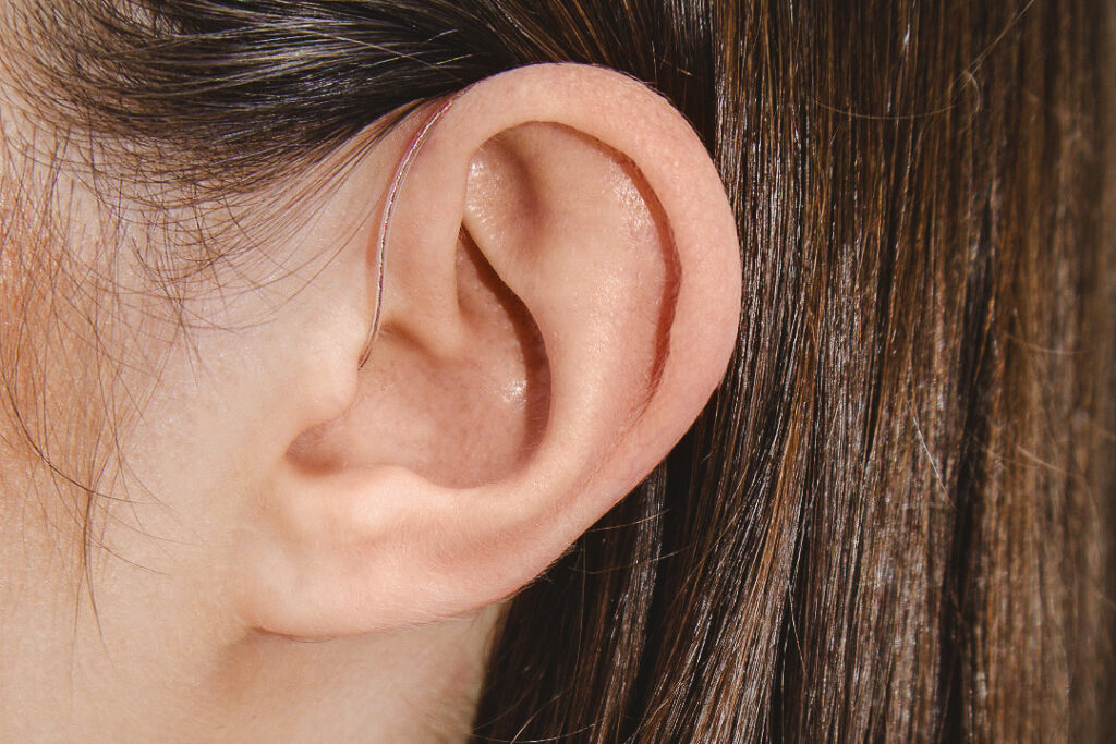 A white woman with brown hair wears a Phonak hearing aid